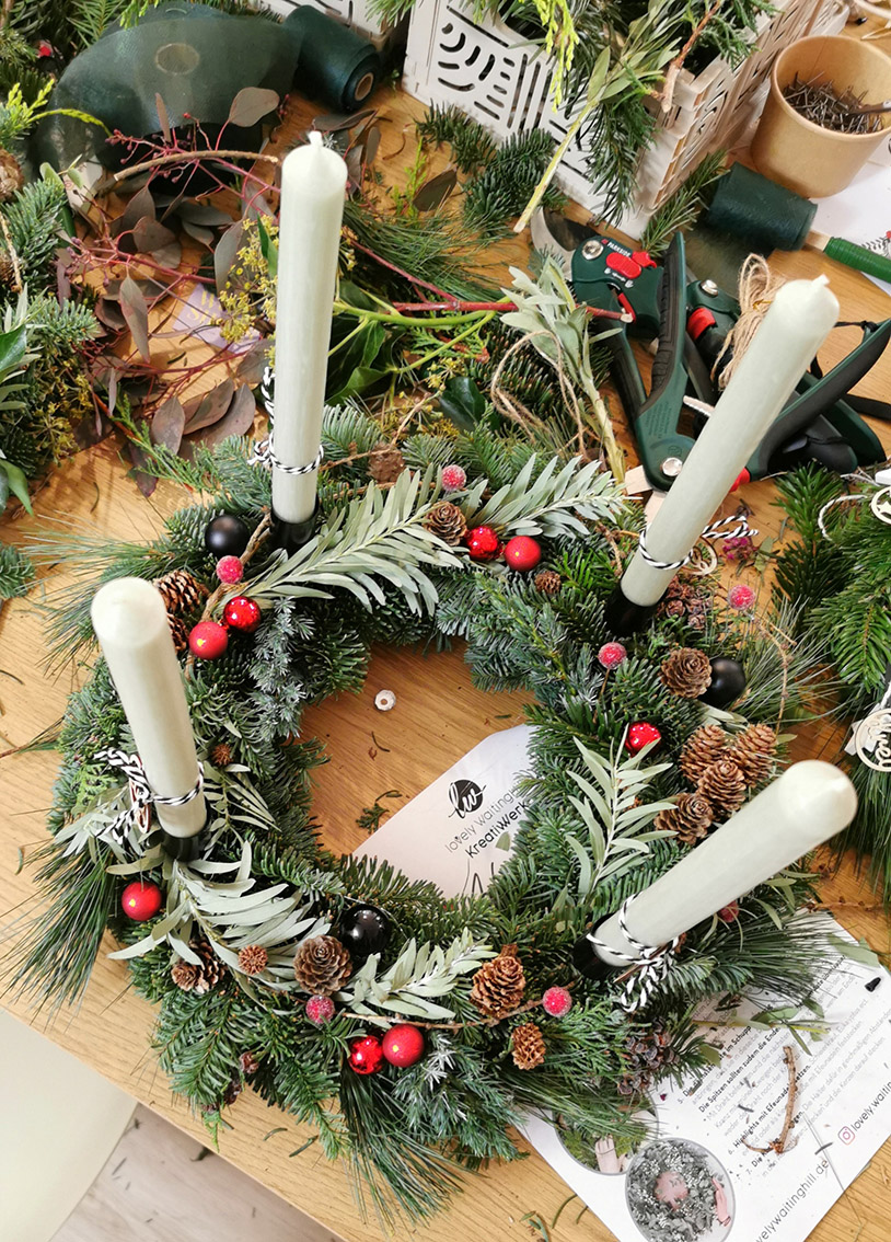 Handgefertigter fertiger Adventskranz aus Tannengrün, Zapfen, Kugeln und Beeren im KreativWerk Pattensen. Mit extra langen Stabkerzen in der Farbe Salbei. Adventskranz-Workshop, Adventskranz selber binden