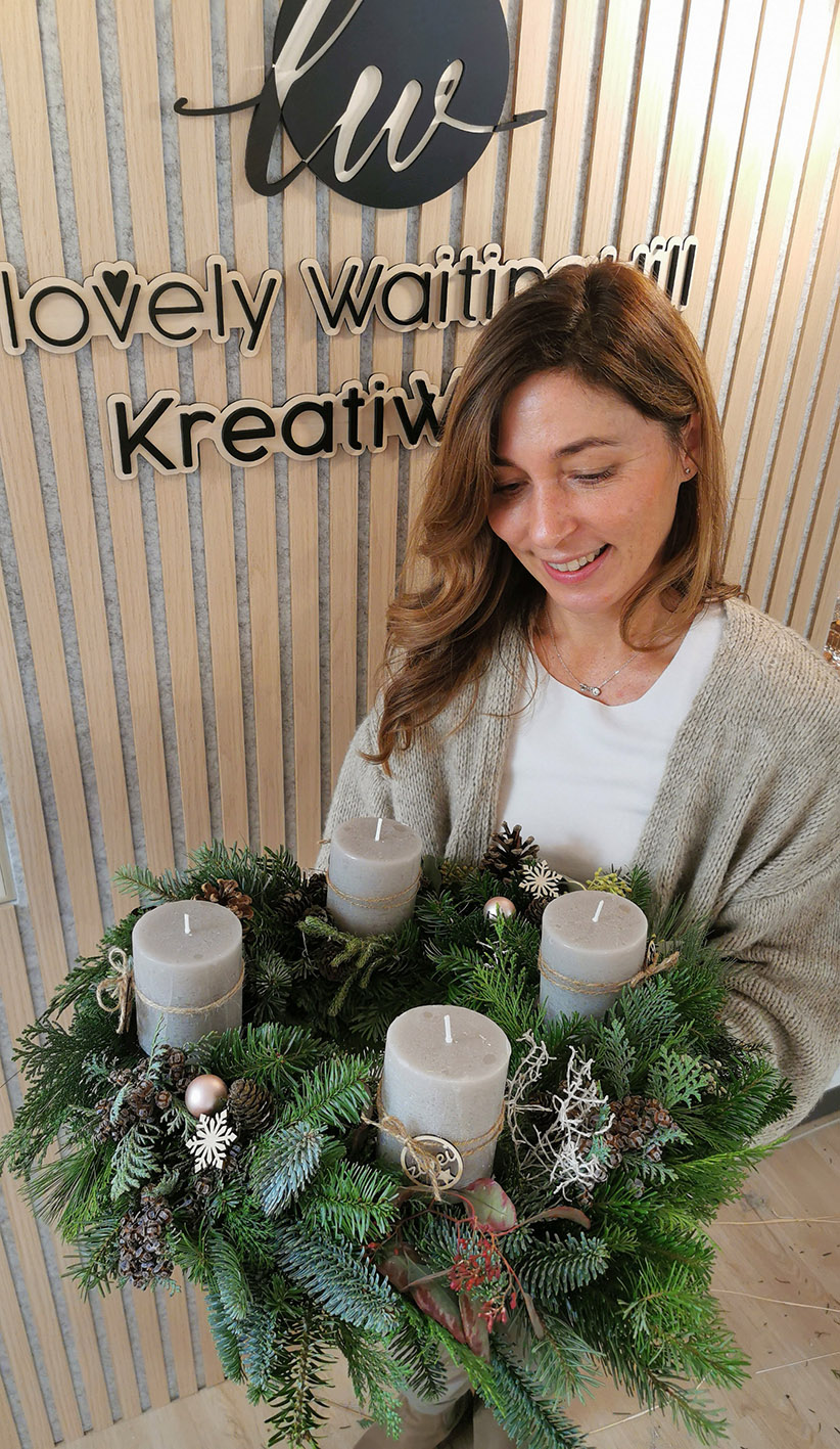 Glückliche Teilnehmerin des Adventskranz Workshops im KreativWerk Pattensen. Wunderschöner selbst gefertigter Adventskranz aus verschiedenem Tannengrün und rustikalen Stumpenkerzen in taube.