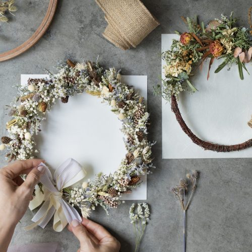 Woman tying a ribbon on a floral wreath Woman tying a ribbon on a floral wreath